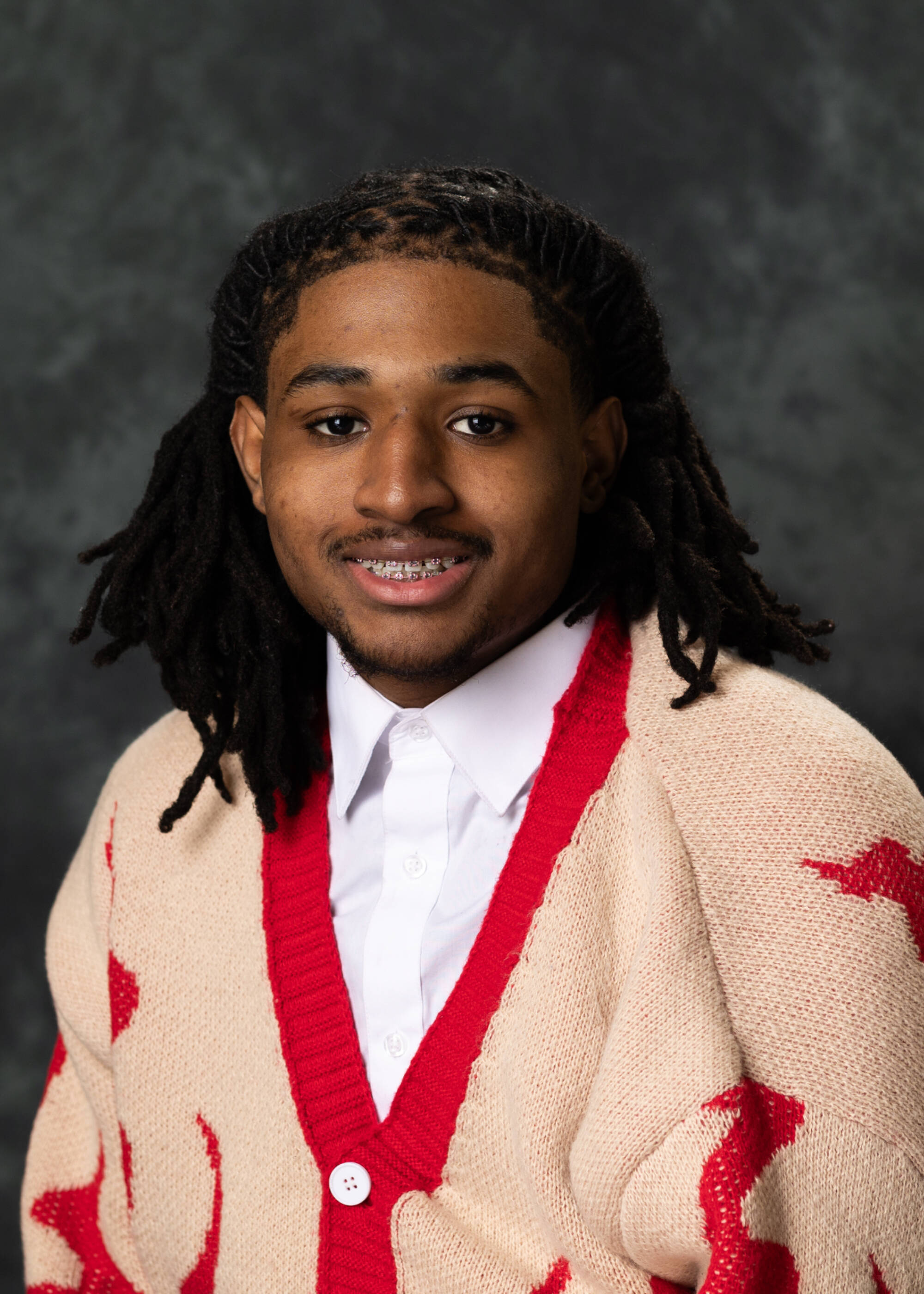 Rashaad Williams smiling in a red and cream-colored cardigan